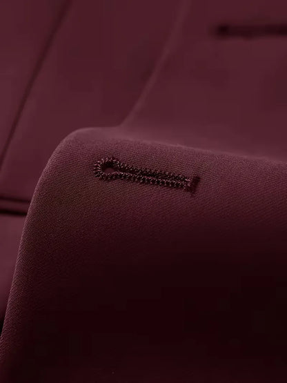 Burgundy suit fabric detail with small stitched logo on inner panel
