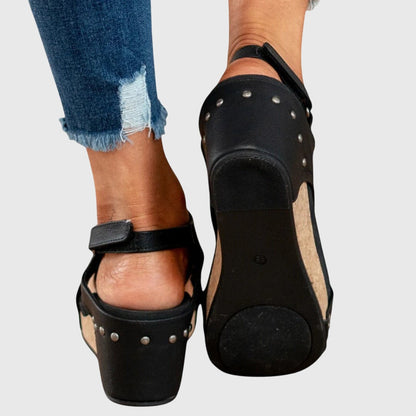 Black orthopedic sandals, back view with stud metal accents and cork-look wedge sole
