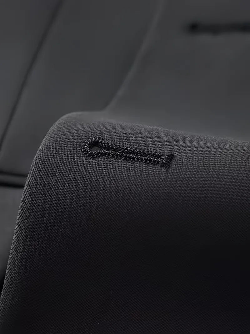 Close-up of black jacket fabric with fine texture and stitched button detail