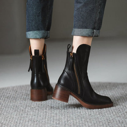 Pair of black ankle boots with side zipper and brown block heel