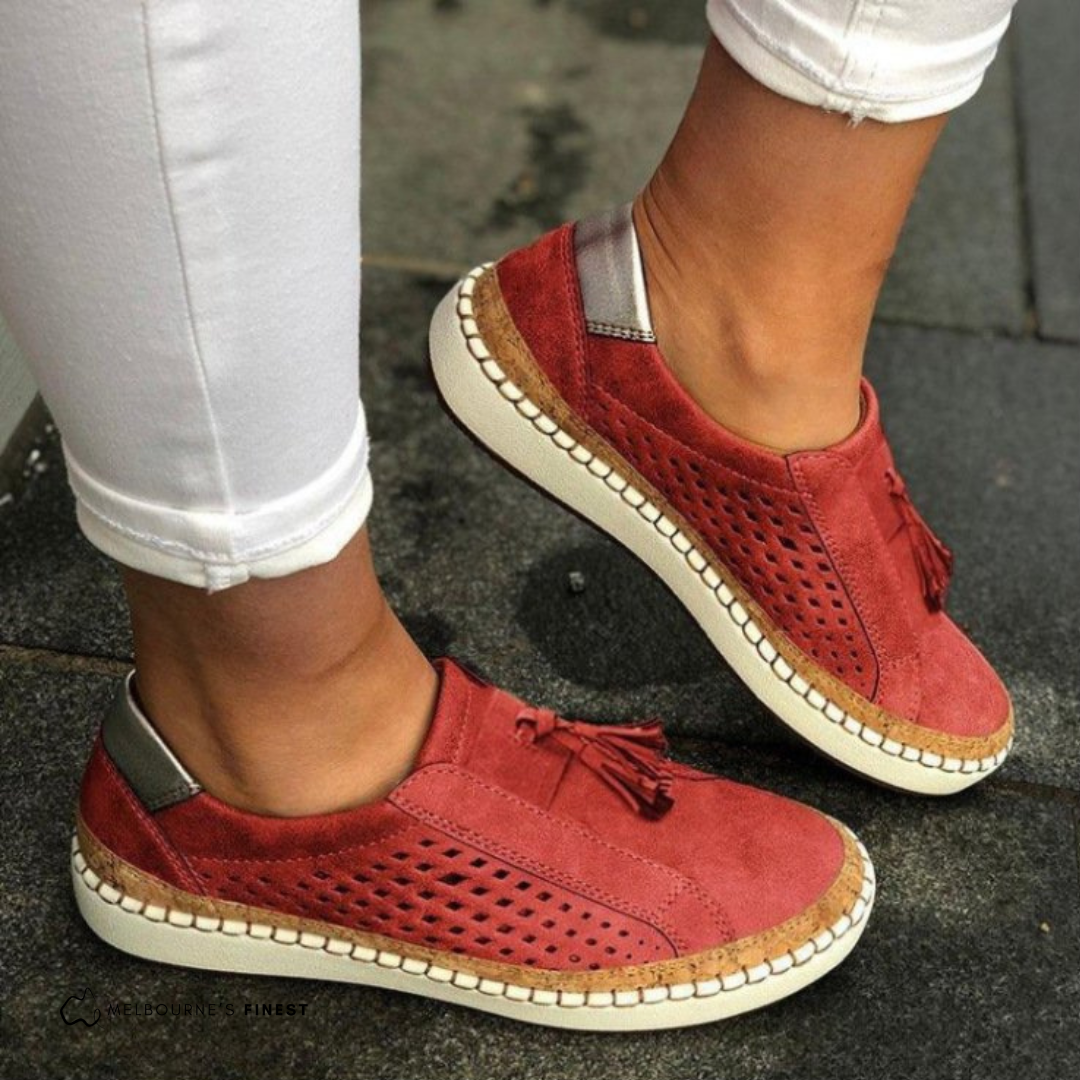 Orthopedic red slip-on shoes with perforated sides, tassel detail, and beige sole