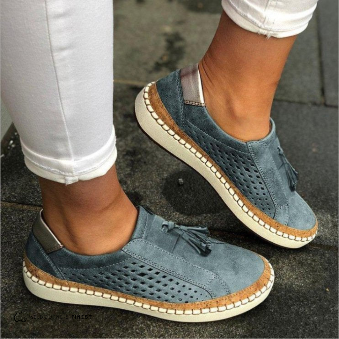 Orthopedic blue slip-on shoes with perforated sides, tassel detail, and beige sole