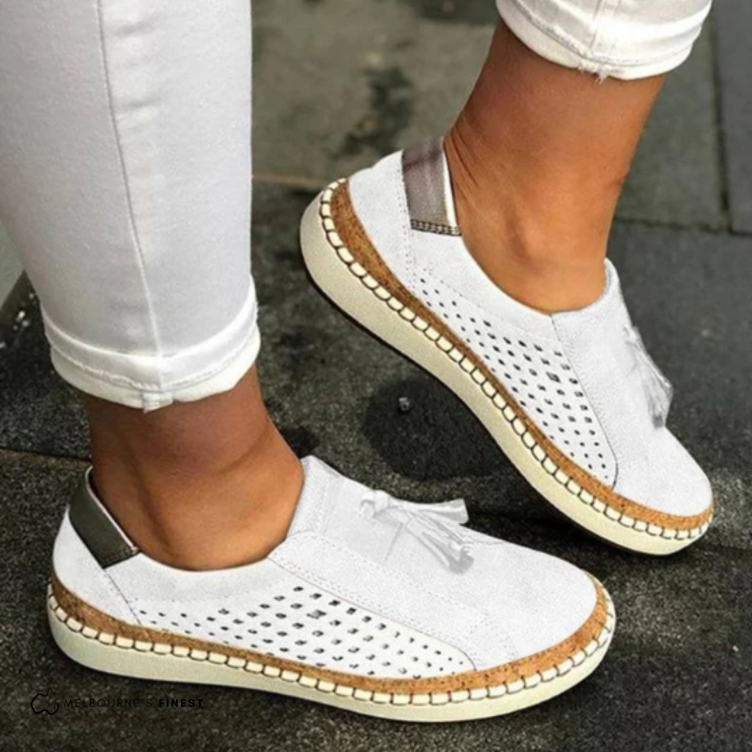 Orthopedic white slip-on shoes with perforated sides, tassel detail, and beige sole