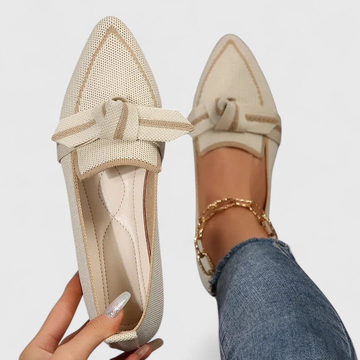 Beige orthopedic loafers with tan edging, lace bow and textured fabric upper.