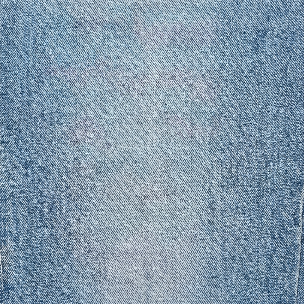 Light blue denim fabric close-up with fine woven texture and seam line
